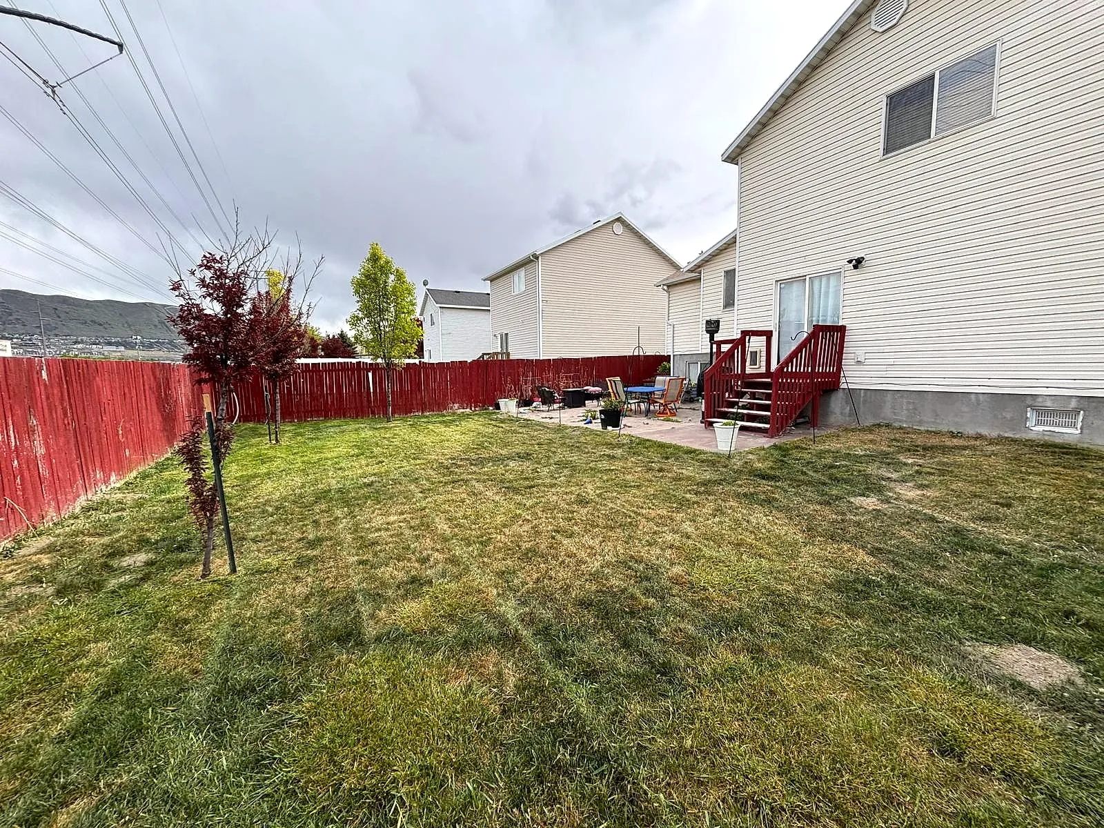 A mowed backyard lawn with even stripes running to a red wooden fence, finished by Taylor’d Lawn Care